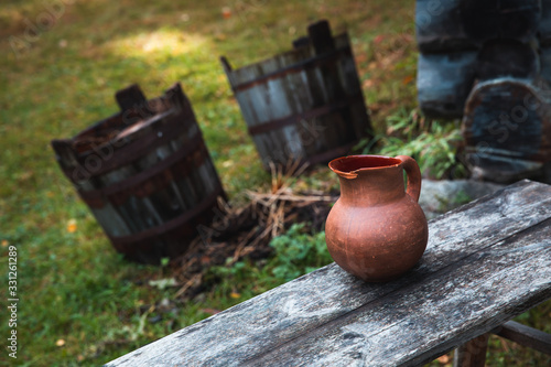 Traditional Estonian Water Jug on a Wooden Bench with Buckets on the background