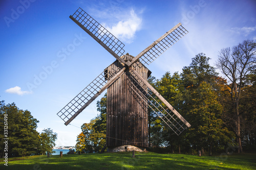 Traditional windmill wooden house on a green grass and under a clear blue sky