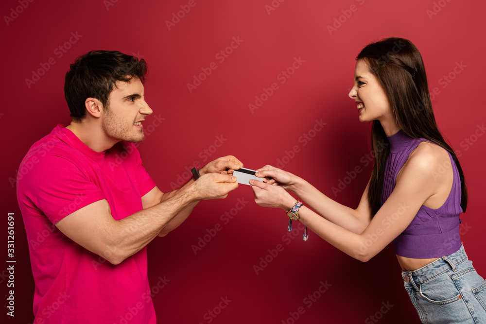 beautiful angry couple pulling credit card on red beautiful angry couple pulling credit card on red