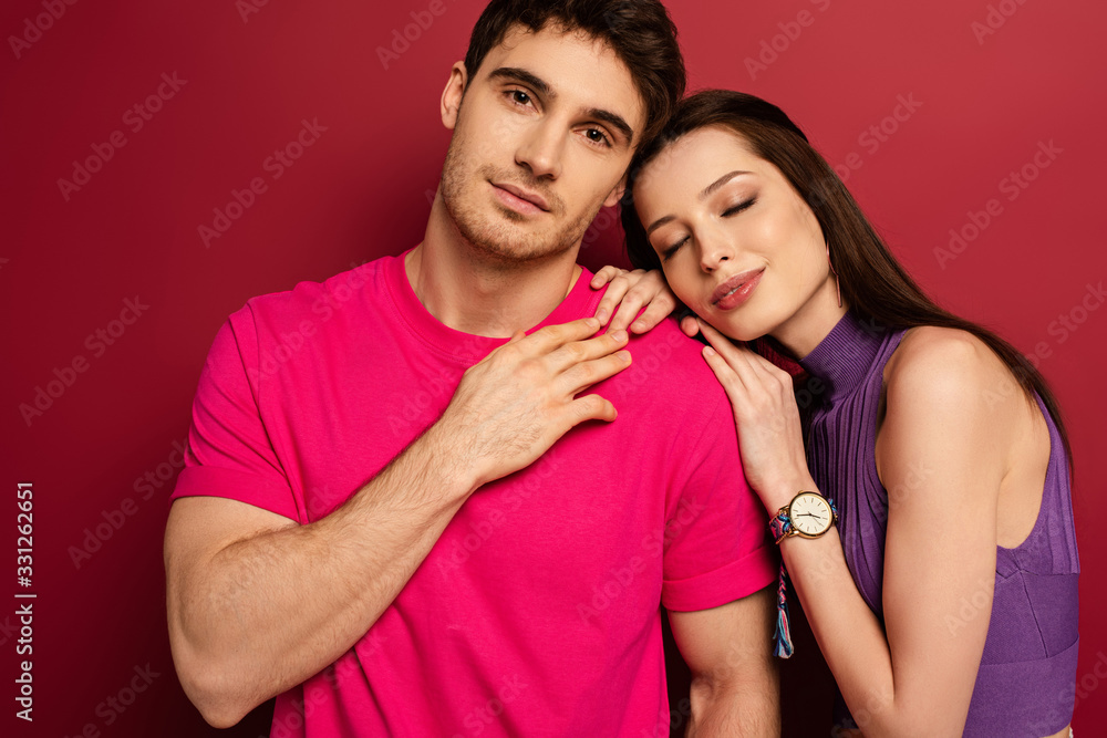 Naklejka premium beautiful young couple hugging with closed eyes on red