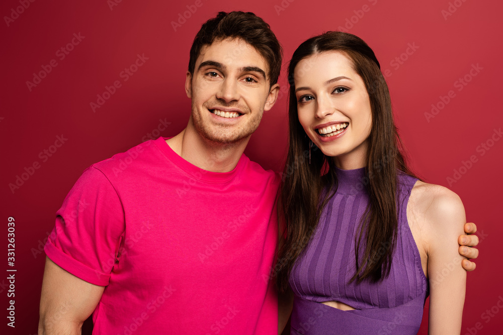 Fototapeta premium beautiful smiling young couple looking at camera on red