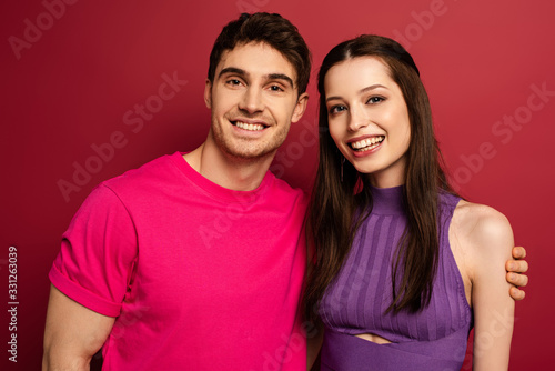 beautiful smiling young couple looking at camera on red