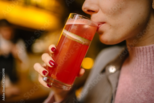 A girl holding on his hand rhubarb cocktail in a highball glass