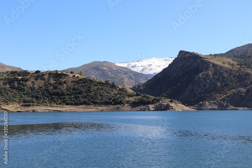 Paisaje con lago azul, montañas verdes y con nieve