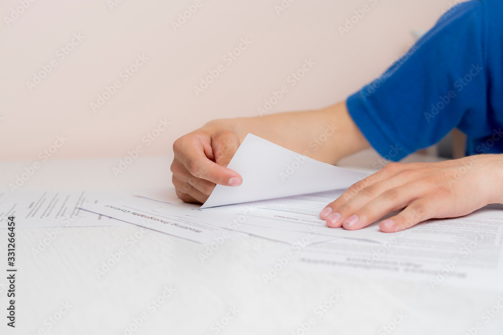 hand holding a document sheet, doing some paper work in the office sitting at the table hand holding a document sheet, doing some paper work in the office sitting at the table
