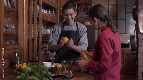 Man and woman smiling, talking, and working together in a restaurant kitchen
