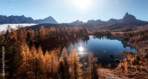 Breathtaking aerial views of the crystal clear Lake Federa in Dolomites Alps under sunlight. A magnificent panorama of the mountains. Impressive autumn landscape, with fog during surise. panorama