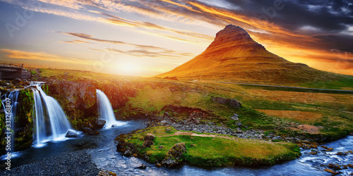 Kirkjufell waterfall and mountain with colorful dramatic sky during sunset, iceland. Amazing nature landscape. Iconic location for landscape photographers. greative artistic image. postcard