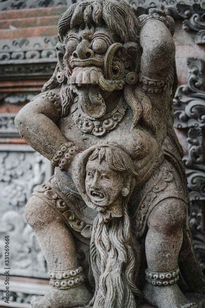 Traditional demon guards statue carved in stone in Bali island