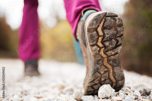 Hiking girl in nature. Low angle view of generic sports shoe and legs on pebble dirt road. Healthy fitness lifestyle outdoors.