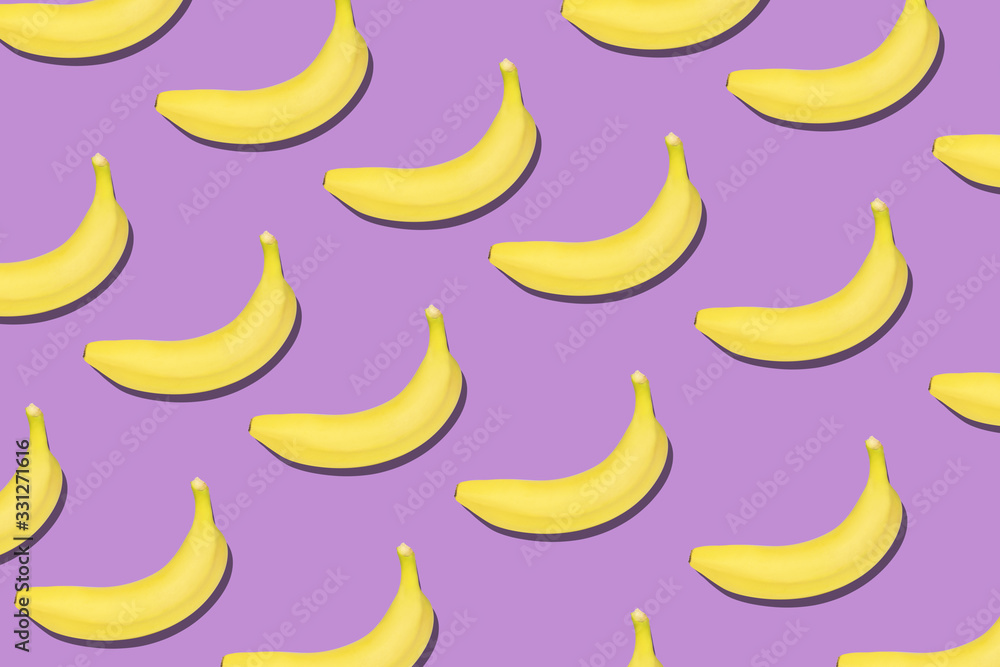 Colorful fruit pattern of fresh yellow bananas on violet background.