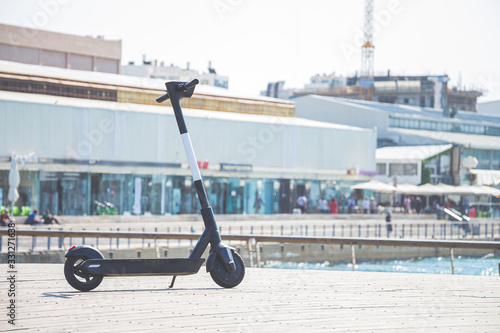 Black electric scooter parking on a deck at Tel Aviv Port commercial district on a summer sunny day