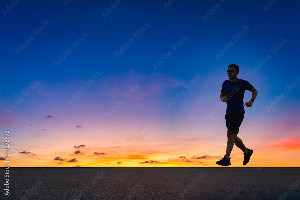 Man running sprinting on road. fit male fitness runner during outdoor workout with sunset background