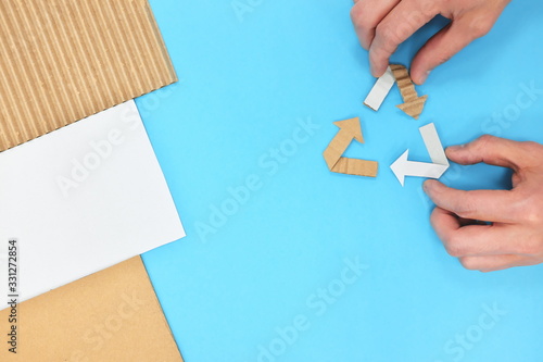 Recyling symbol flat lay with human hands. Recycled paper cardboard. photo