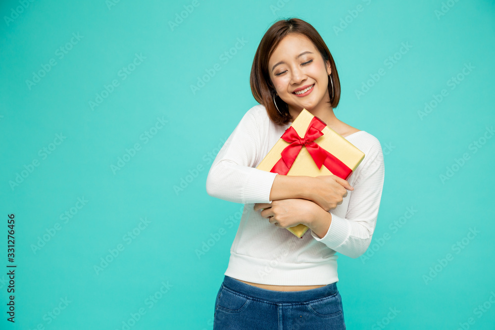 Happy beautiful asian woman smile with gold gift box isolated on green background. Teenage girls in love, Receiving gifts from lovers. New Year or Christmas concept Happy beautiful asian woman smile with gold gift box isolated on green background. Teenage girls in love, Receiving gifts from lovers. New Year or Christmas concept