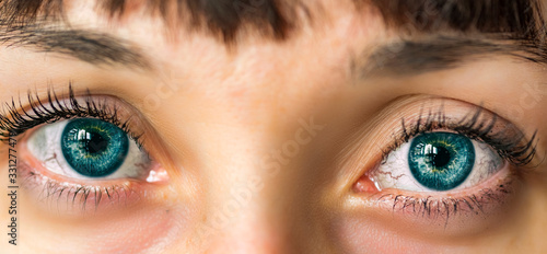 The turquoise eyes of a girl photographed very close-up.