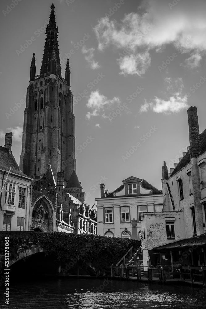 Church Of Our Lady and traditional narrow streets in Bruges. Bridge over canala in a foreground.