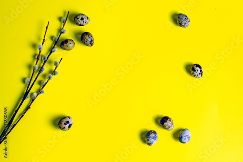 Easter frame from quail eggs, willow branches on a yellow background. Creative layout for text for Easter. Easter card on a yellow background