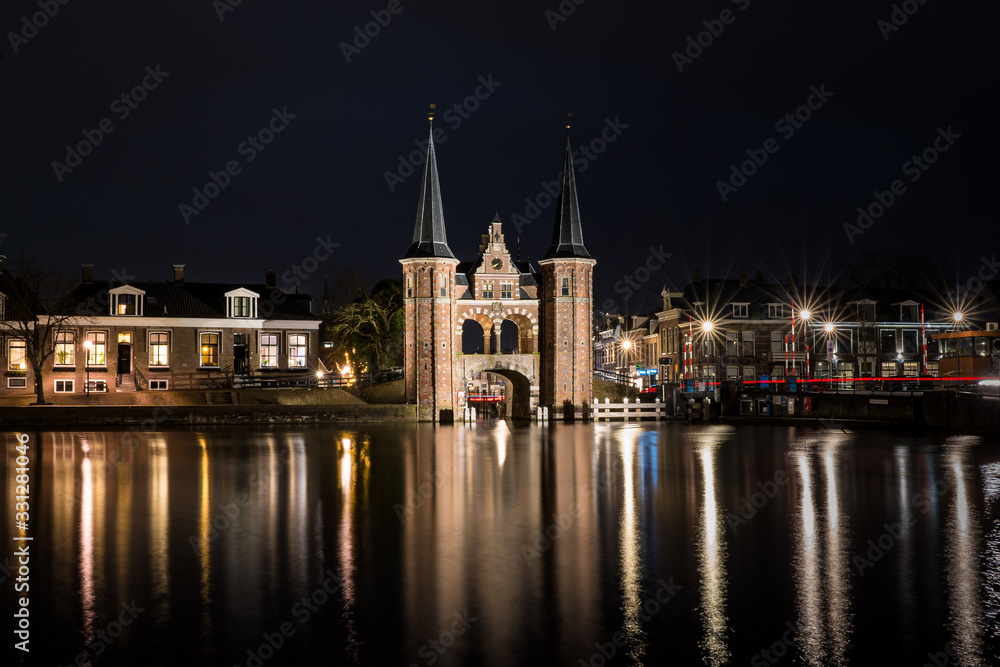 The famous historical 'Waterpoort' in the city of Sneek at night with reflections in the canal - Sneek, Friesland, The Netherlands