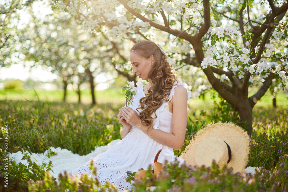 The beautiful girl the blonde in the blossoming apple-trees garden The beautiful girl the blonde in the blossoming apple-trees garden