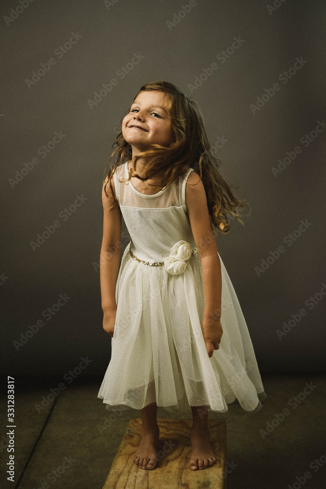 A young girl on gray background makes a funny face