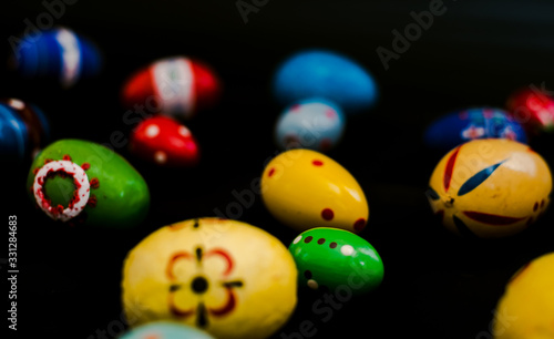 multicolored wooden eggs on black background