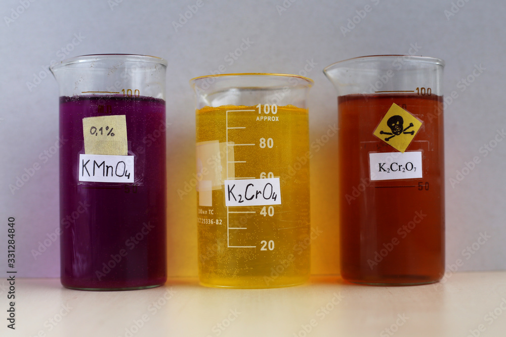 Three beakers with aqueous solutions of salts, oxidizing agents purple