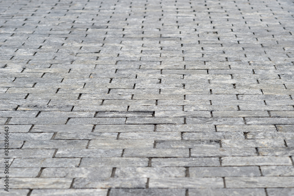 The sidewalk is made of rectangular gray granite bricks . Background