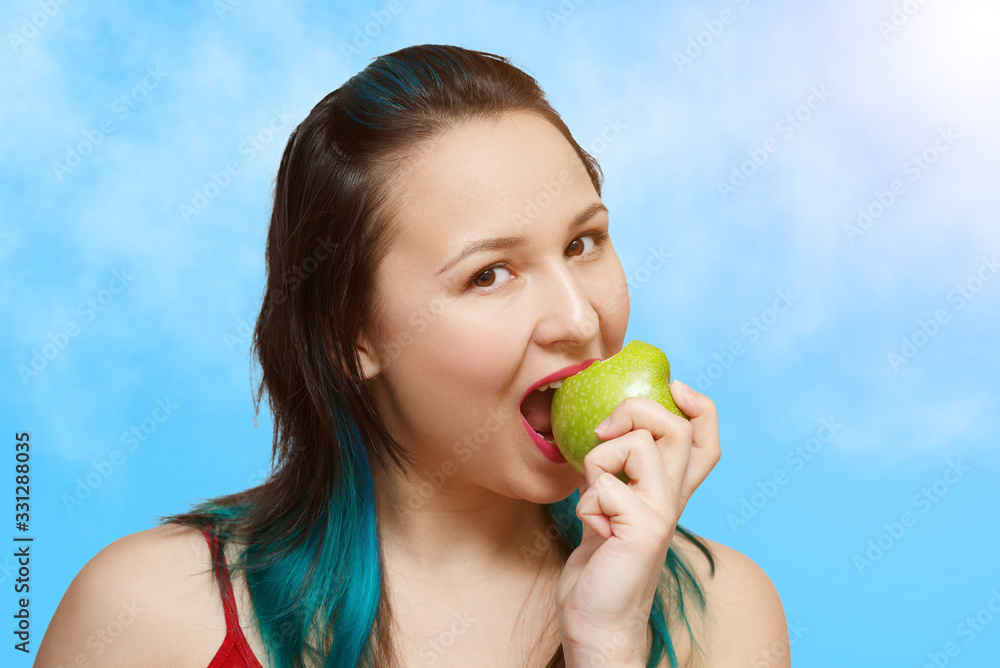 young beautiful girl eating an Apple. on a blue sky background young beautiful girl eating an Apple. on a blue sky background