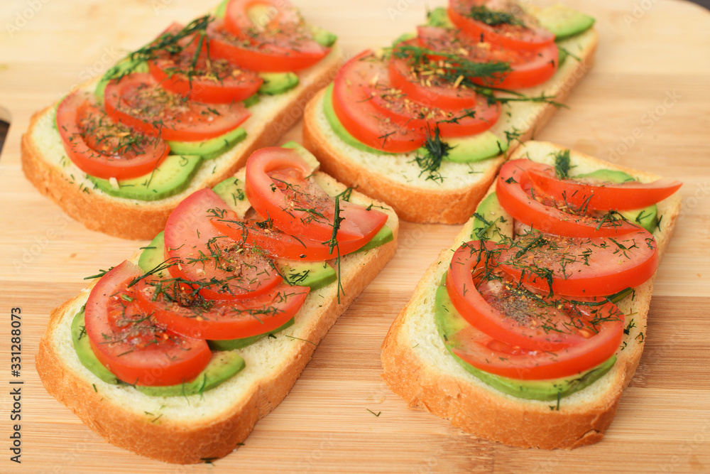 sandwiches with fresh avocados, tomatoes and greens on wooden Board background. side view