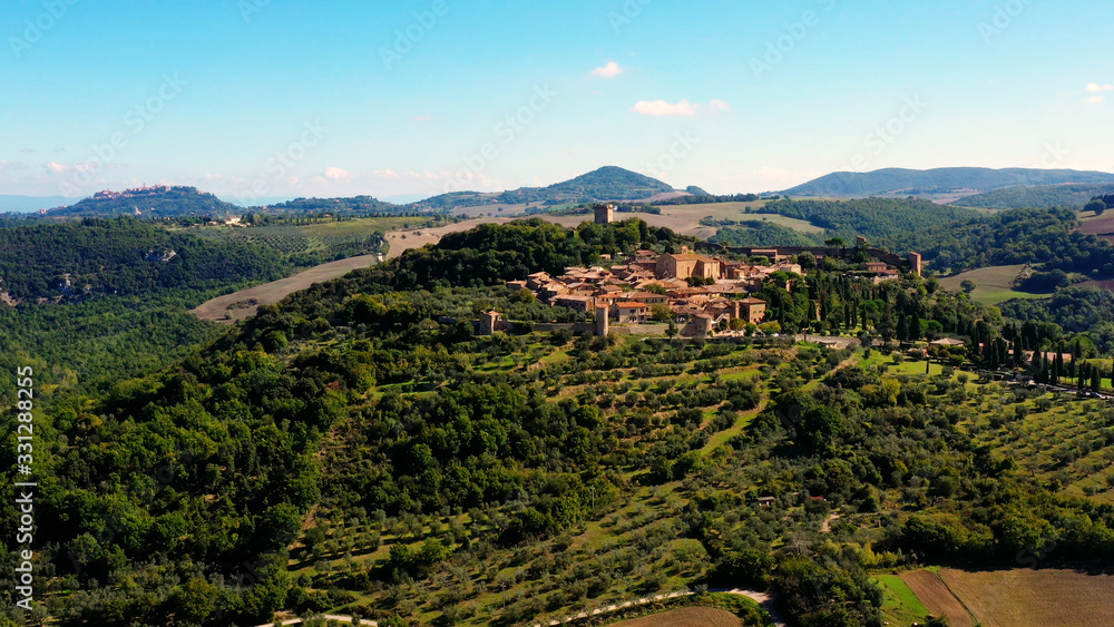 Obraz premium Italian village of Monticchiello in Tuscany, Italy. Drone flying over the magnificent village and green meadows. Perfect for authentic travelling in Italy 