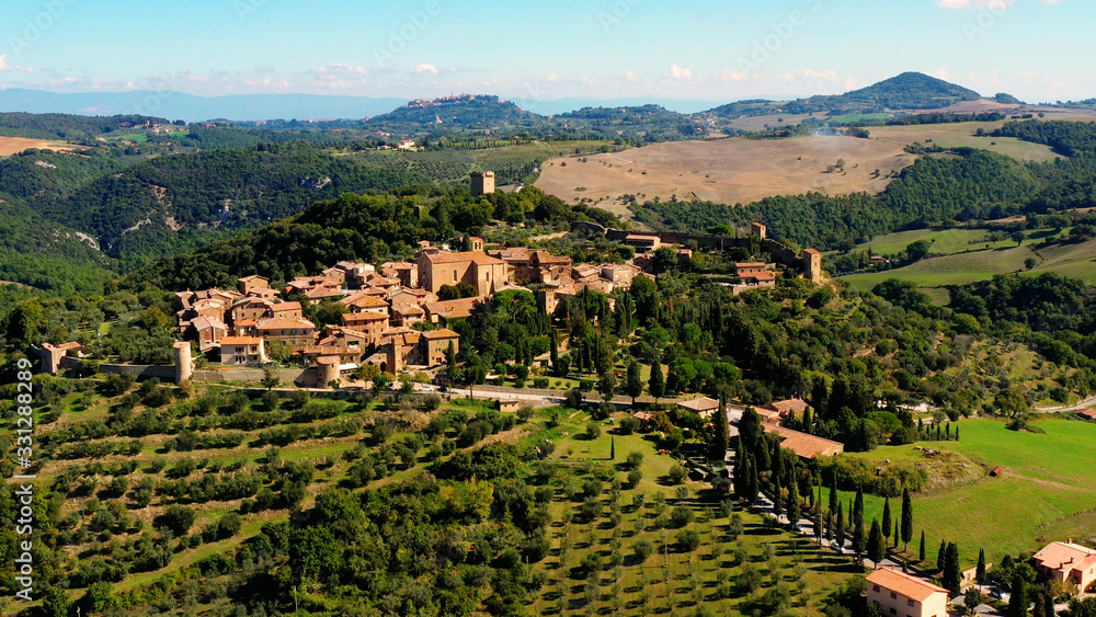An Italian village with green meadows all over the village. Aerial view with a drone of the beautiful and old village of Monticchiello in Tuscany, Italy