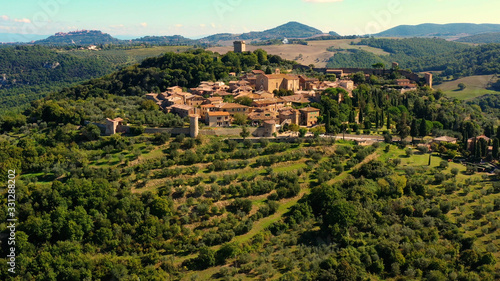 An Italian village with green meadows all over the village. Aerial view with a drone of the beautiful and old village of Monticchiello in Tuscany, Italy	
