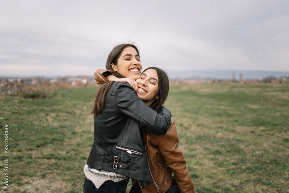 Beautiful sisters cuddling in the park during day