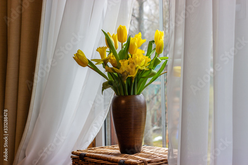 Bouquet of yellow tulips and daffodils  in a vase. Easter and spring greeting card. Women's day, March 8.
