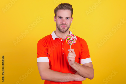 Taste the rainbow. Man candy yellow background. Handsome guy hold candy on stick. Candy shop. Lollipop or sucker. Sugary treat. Candy factory and confectionary