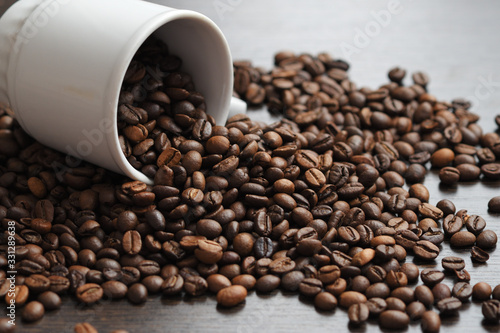 coffee beans are poured from a white Cup on a wooden surface.