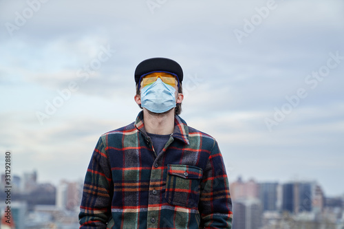 Hope coronavirus theme: young hipster man in medical mask and goggles looking to the sky © boytsov