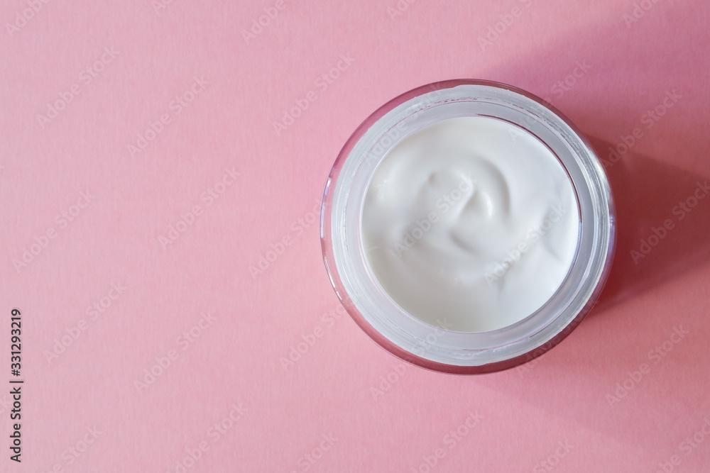 An open glass jar with white cream for the face or body on a pink background. Skincare concept. Horizontal orientation. Copy Space. Top view. An open glass jar with white cream for the face or body on a pink background. Skincare concept. Horizontal orientation. Copy Space. Top view.