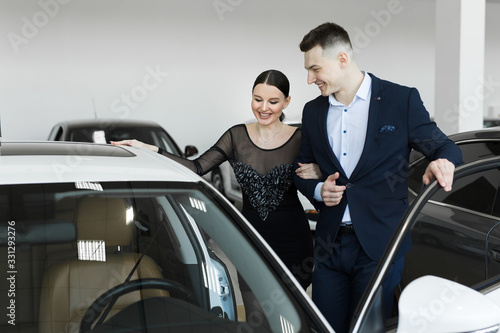 A couple husband and wife choose a car to buy at a car dealership