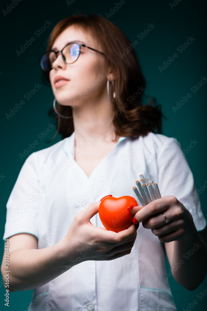 Young cardiologist holds a toy red heart, showing that people monitor their health and did not use nicotine Young cardiologist holds a toy red heart, showing that people monitor their health and did not use nicotine