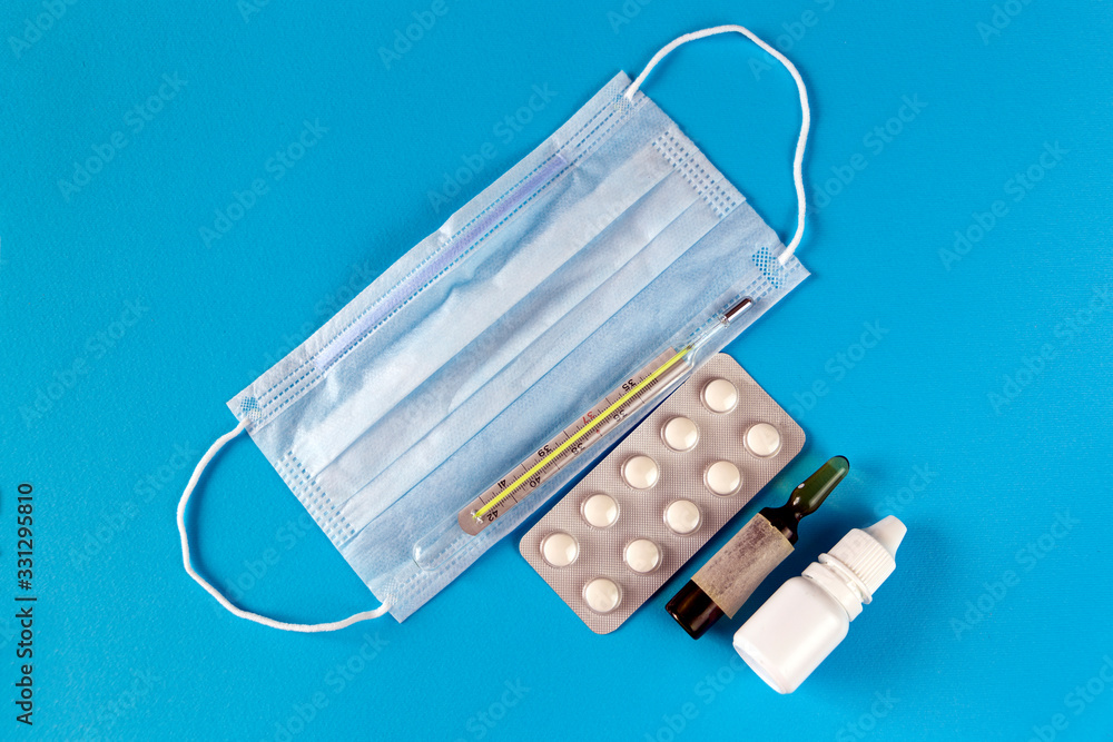 medical treatment from virus: face mask, pills, drops, thermometer on the blue background medical treatment from virus: face mask, pills, drops, thermometer on the blue background