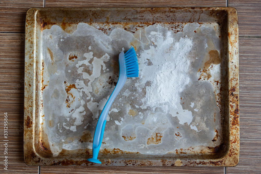 dirty aluminum baking sheet. Cleaning the pan with a cleaning agent and a brush