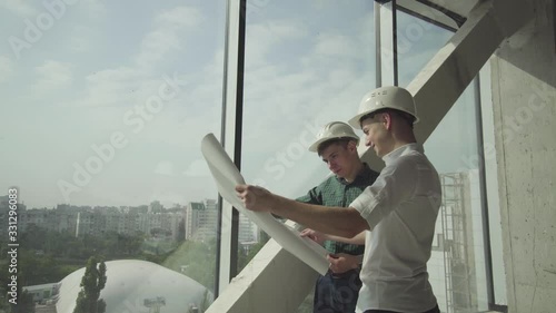 Two young architects verify the execution of the construction work in an office building