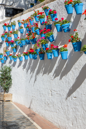 Beautiful old town center of Marbella city in a sunny day of December. White wall decorated with blue flower pot. © alexemarcel