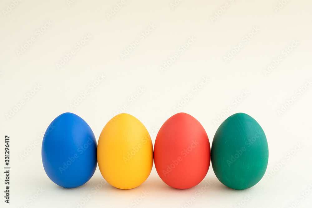 four easter eggs of different colors stay in row in front, white background, copyspace, layout for greeting card, easter holiday concept