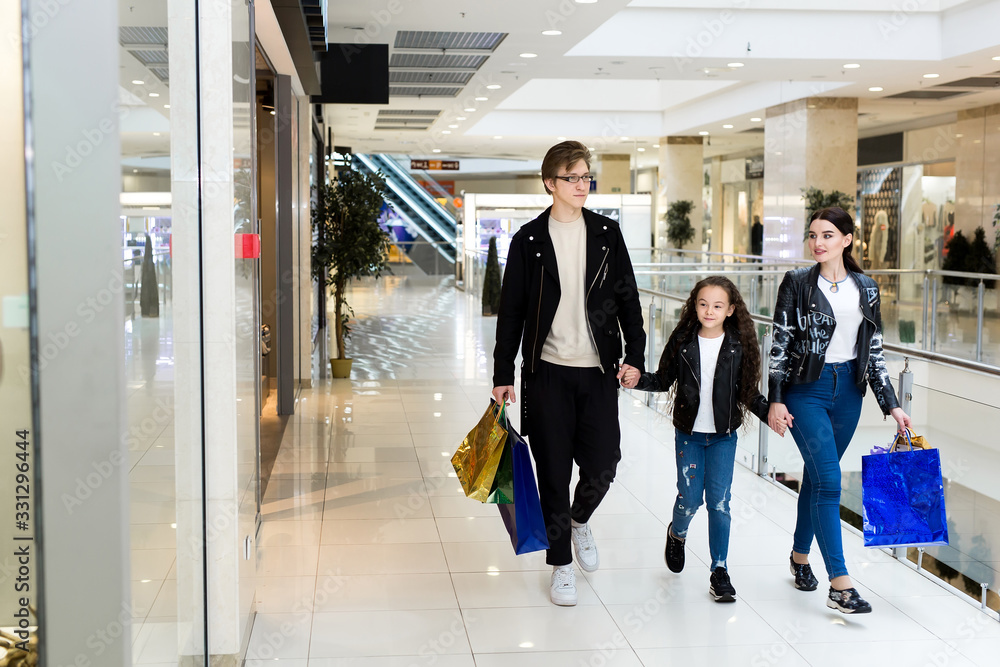 Happy young family with paper bags shopping at the Mall. Shop Windows with clothes