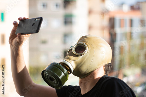 Man in a gas mask taking a selfie with his smartphone in a city. Apocalypse, coronavirus photo