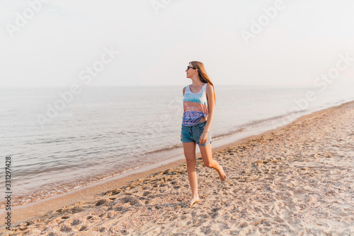 Young girl strolling along the beach enjoying the Sunny weather