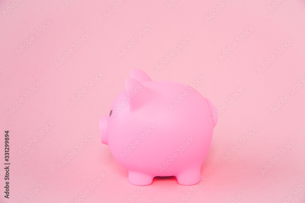 A pink childrens piggy bank on a pink background with copy space
